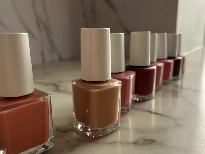 Reihe von Nagellack- und Gelfarben in Nude-, Rosé- und Beerentönen auf Marmor